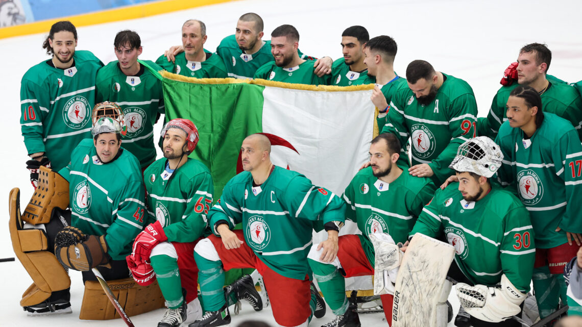 A photo of the Algeria national ice hockey team wearing green uniforms holding a large Algeria flag